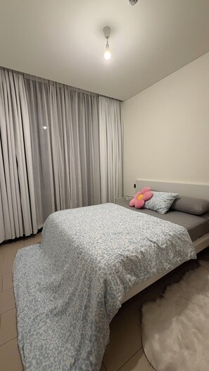 A bedroom with a bed, a large window with curtains, a ceiling light, and a fluffy rug. - Cozy 1-bedroom apartment in excellent view near dubai mall , burj khalifa (Dubai)