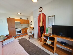 Ein kompakter Wohnraum mit Küchenzeile, Essbereich und einer Sitzecke mit Fernseher.