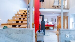Een modern interieur met een trap, een rode accentmuur, een bed en een keukenhoek.