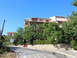 A multi-story residential building with balconies, surrounded by greenery and a stone wall. - "Manda3" mit Blick auf das Wasser by Interhome (Novi Vinodolski)
