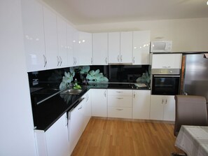 A modern kitchen with white cabinets, black countertops, a stainless steel refrigerator, and a built-in oven. - "Manda3" mit Blick auf das Wasser by Interhome (Novi Vinodolski)