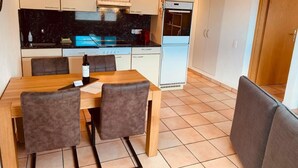 A compact kitchen with a dining table, chairs, and a refrigerator. - Ai Ronchi by Interhome (Gordola)