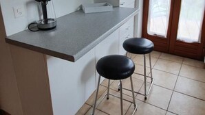 A kitchen with a grey countertop, two black stools, and a window with sheer curtains. - mit Bergblick by Interhome (Gordola)