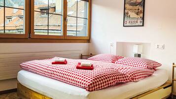 Ein Hotelzimmer mit Bett, Fenster, einem Poster an der Wand und Blick auf Gebäude.