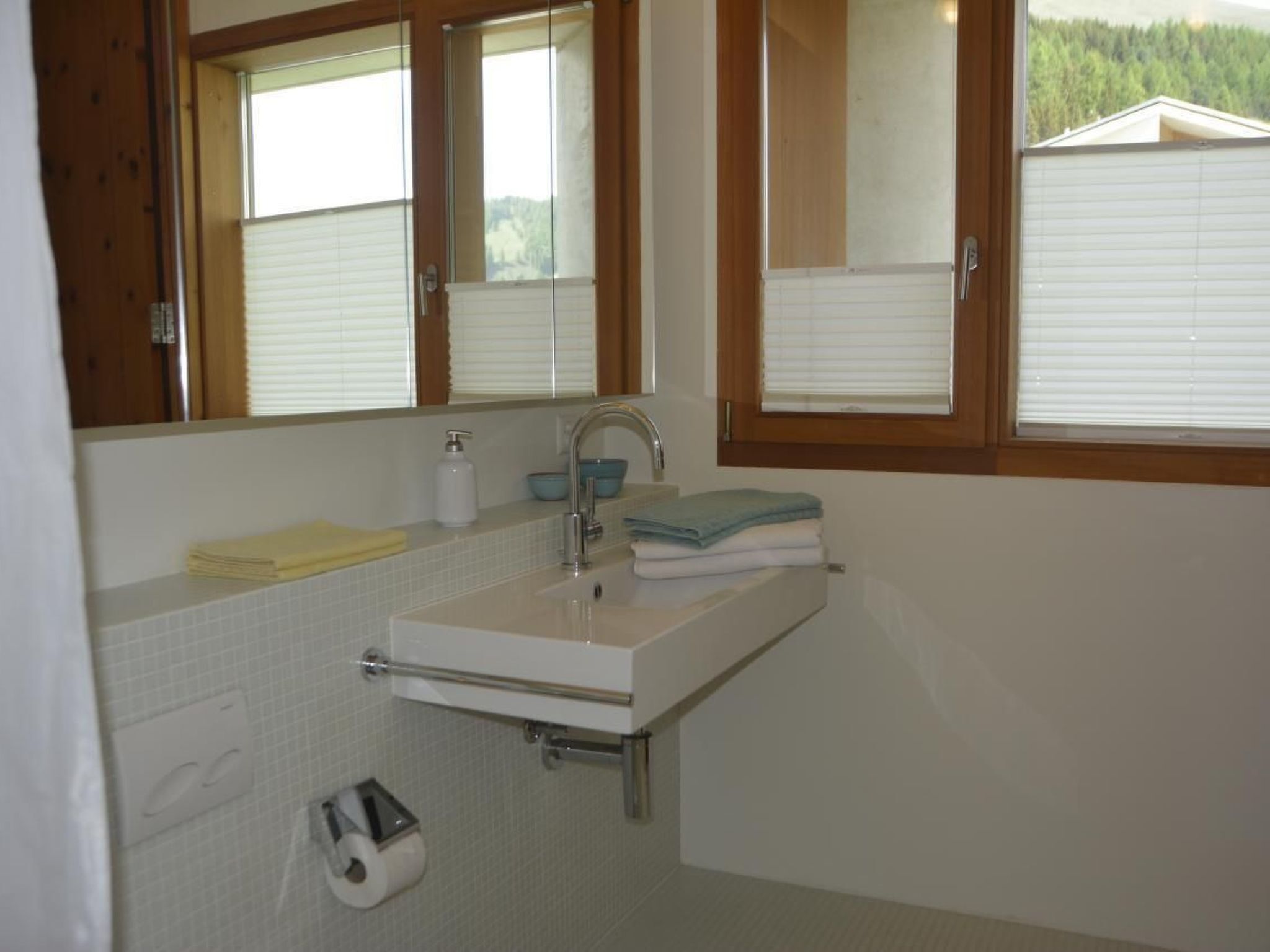Une salle de bain avec un lavabo, un miroir et une fenêtre.