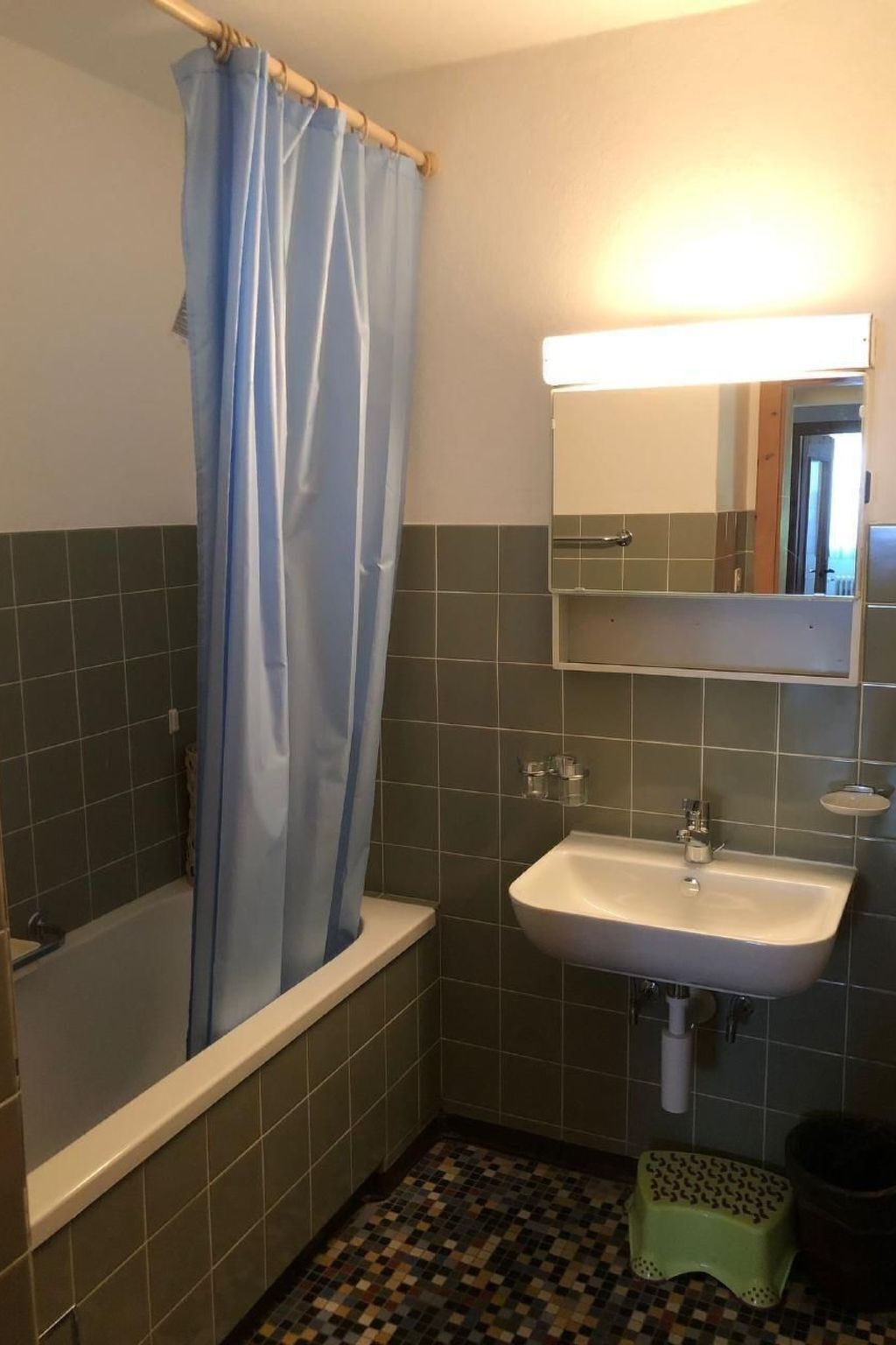 Un bagno con una vasca, un lavandino, uno specchio e una tenda da doccia.