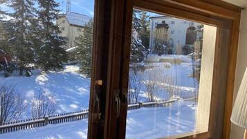 Ein Fenster mit Blick auf eine verschneite Landschaft, einschließlich Bäumen und Gebäuden.