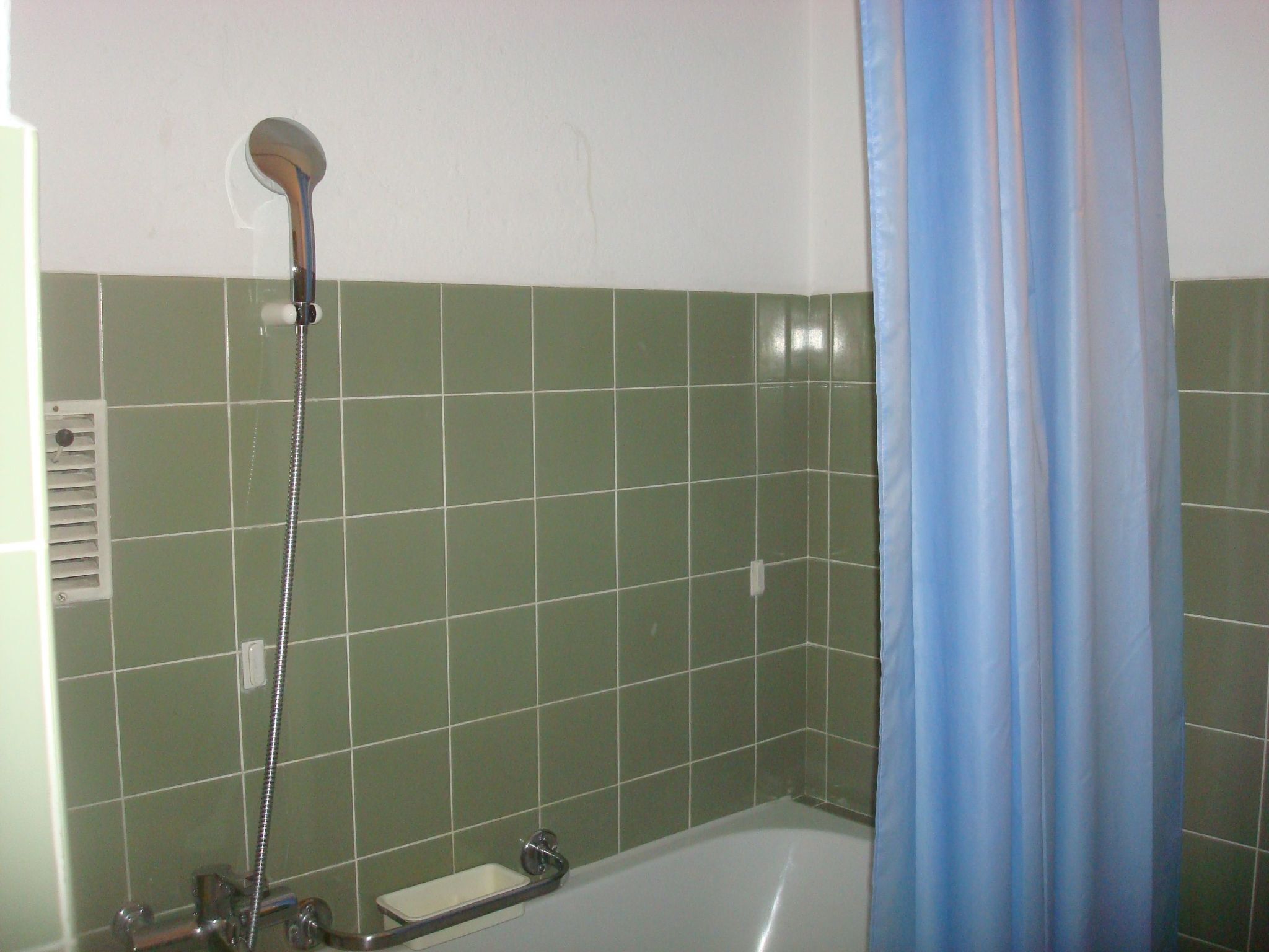Bany amb dutxa, banyera i cortina blava.