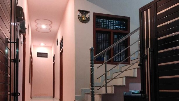 Un escalier moderne avec une rampe en métal, menant à un palier doté d’une petite fenêtre.