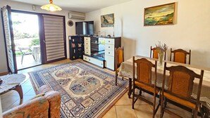 A living room with a dining area, a TV, a painting, and a view through a sliding door. - für 6 Personen in Klenovica by Interhome (Novi Vinodolski/Klenovica)