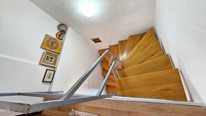 A wooden staircase with a metal handrail, white walls, and a ceiling light. - für 6 Personen in Klenovica by Interhome (Novi Vinodolski/Klenovica)