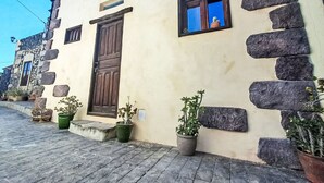 Un edifici amb façana de pedra, una porta de fusta i una finestra petita que dona al cel.