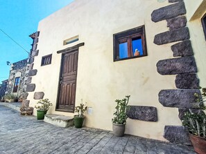 A building with a stone facade, a wooden door, and a small window with a view of the sky. - Vacation home Trina by Interhome (Igueste)
