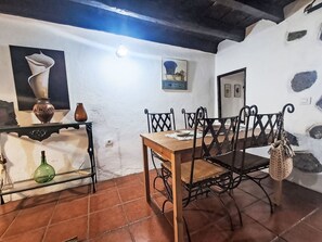 A dining area with a wooden table and chairs, a shelf with decorative items, and a wall with a painting. - Vacation home Trina by Interhome (Igueste)