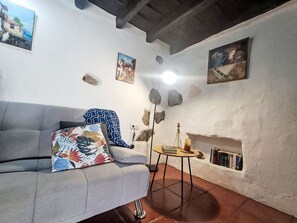 A living room with a grey sofa, a small round table, a fireplace, and wall-mounted paintings. - Vacation home Trina by Interhome (Igueste)
