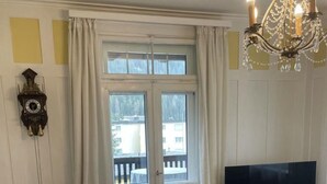 Ein Essbereich mit Tisch, Stühlen, einem Fernseher und einer Chandelüstere.