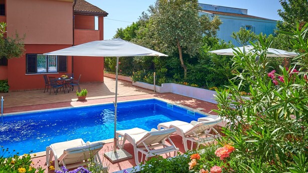 Ein Schwimmbecken mit Liegestühlen, einem Tisch mit Stühlen und einem Blumentopf.