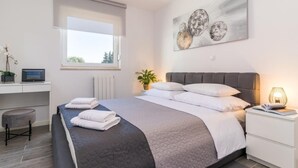 A modern bedroom with a large bed, a desk, and a window. - Wohnung mit Blick auf das Wasser by Interhome (Pula)