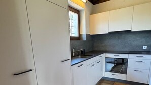 A kitchen with white cabinets, a black countertop, and a window. - Casa Rena by Interhome (Ascona)