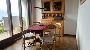 A dining area with a wooden table and chairs, a cabinet with glass doors, and a view through large windows. - Casa Rena by Interhome (Ascona)
