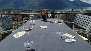 An outdoor dining table with wine glasses and playing cards, overlooking a mountainous landscape and a body of water. - Casa Rena by Interhome (Ascona)