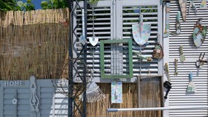 A white gate labeled "HOME" with a bamboo fence, a metal gate, and a decorative wall with various items. - Haus in Pula mit privatem Pool by Interhome (Pula)