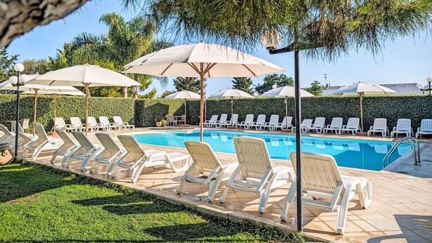 Ein Poolbereich mit Liegestühlen und Sonnenschirmen.