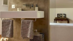 A modern bathroom with a large mirror, a sink, and two towels hanging on hooks. - Maisonettewohnung in Residenz des Giardino Ascona by Interhome (Ascona)