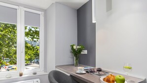 A modern kitchen with a window, grey chairs, a dining table with a plate of food, a vase with flowers, and a white air conditioner. - Wohnung "InCenter Wohnung 2" by Interhome (Rijeka)