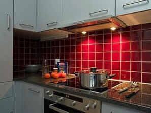 Een koelkast, een oven, een vaatwasser, kookgerei, borden en bestek