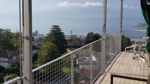 Un balcón con vistas a montañas y una ciudad.
