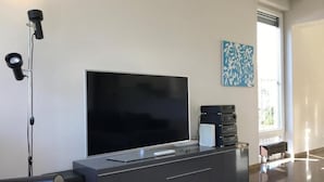 Una sala de estar moderna con un televisor de pantalla plana grande, un mueble de entretenimiento gris y un sofá rojo.