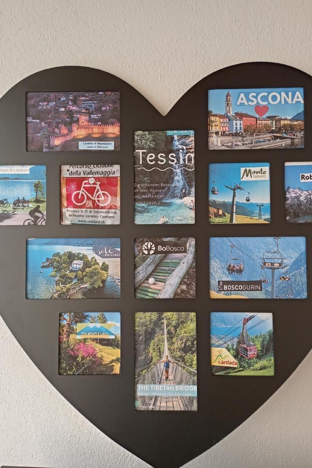Un présentoir en forme de cœur où sont exposées différentes cartes postales sur le thème du voyage.