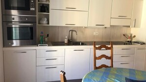 A modern kitchen with stainless steel appliances, white cabinetry, and a wooden chair. - Zwischen Locarno und Ascona ganze Wohnung by Interhome (Locarno)