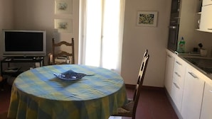 A dining area with a round table covered by a blue and yellow tablecloth, a television on a stand, and a door leading outside. - Zwischen Locarno und Ascona ganze Wohnung by Interhome (Locarno)