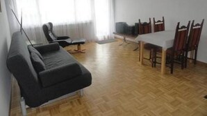 Una stanza con un divano, un tavolo da pranzo con sedie e una finestra con tende.