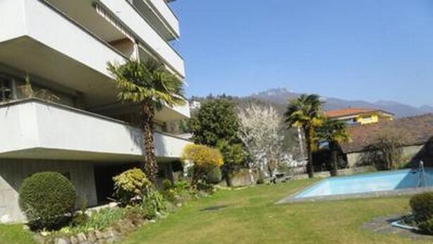 Un edificio moderno con piscina, circondato da prati curati e alberi.