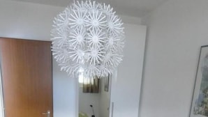 Una camera da letto con un letto, uno specchio e una lampada a soffitto bianca.