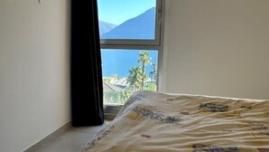 Ein Schlafzimmer mit einem Bett, einem Fenster mit Bergblick und einem Vorhang.
