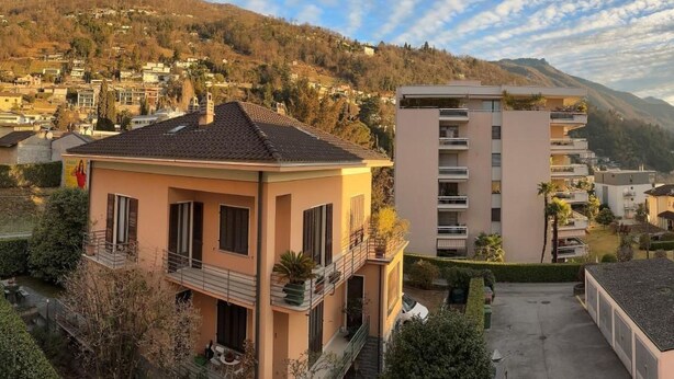 Ein Wohngebäude mit Balkon und Blick auf eine an einem Hang liegende Stadt.