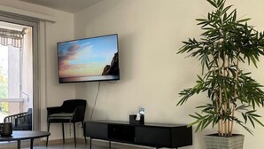 Ein modernes Wohnzimmer mit einem an der Wand montierten Flachbildfernseher, einem schwarzen Konsolentisch, einem roten Teppich und einer großen Kübelpflanze mit Bambus.