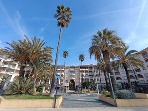 Ein Hotel mit Innenhof, Palmen und einem Gebäude mit mehreren Balkonen.