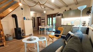 A cozy living room with a sofa, a dining table, and a kitchen area. - mit Jacuzzi by Interhome (Kopalino)