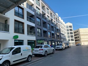 Ein mehrstöckiges Gebäude mit Balkonen, einem Schild mit der Aufschrift 'HolidayHome' und parkenden Autos.
