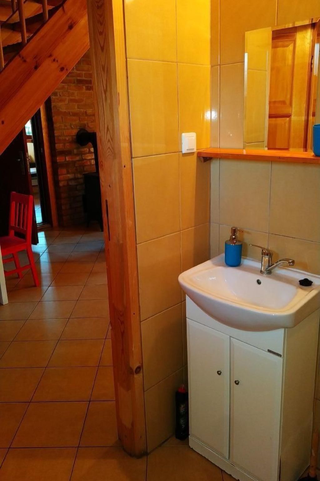 Een badkamer met een witte wastafel, houten kastjes en een spiegel erboven.