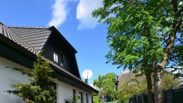 A narrow pathway leading to a traditional house with a tiled roof, surrounded by greenery and trees. - Haus Komoran by Interhome (Baabe)
