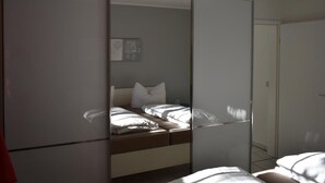 Un dormitorio con cama, armario y espejo.