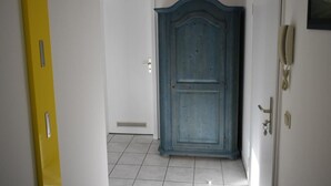 Un pasillo con una puerta azul, una puerta blanca y una pared amarilla.