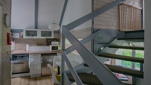 Una cucina moderna con lavastoviglie integrata, un forno a microonde e una macchina da caffè. Una scala con ringhiera in legno conduce a un balcone.