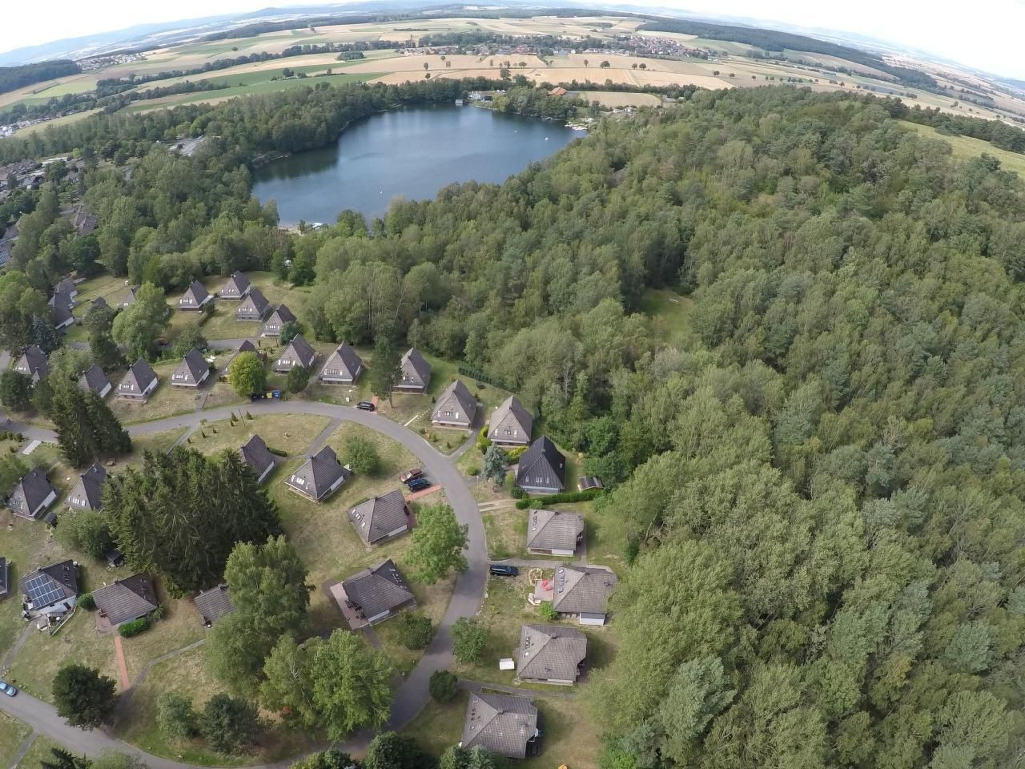 Vista aérea de una zona residencial con casas dispuestas en semicírculo alrededor de un lago central.